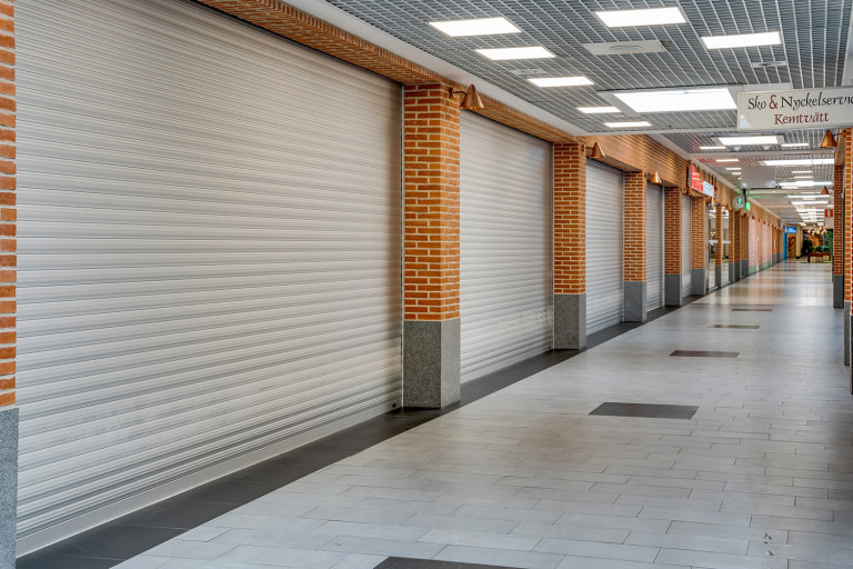Korridor med skyddsklassade rulljalusi framför butiksentréer